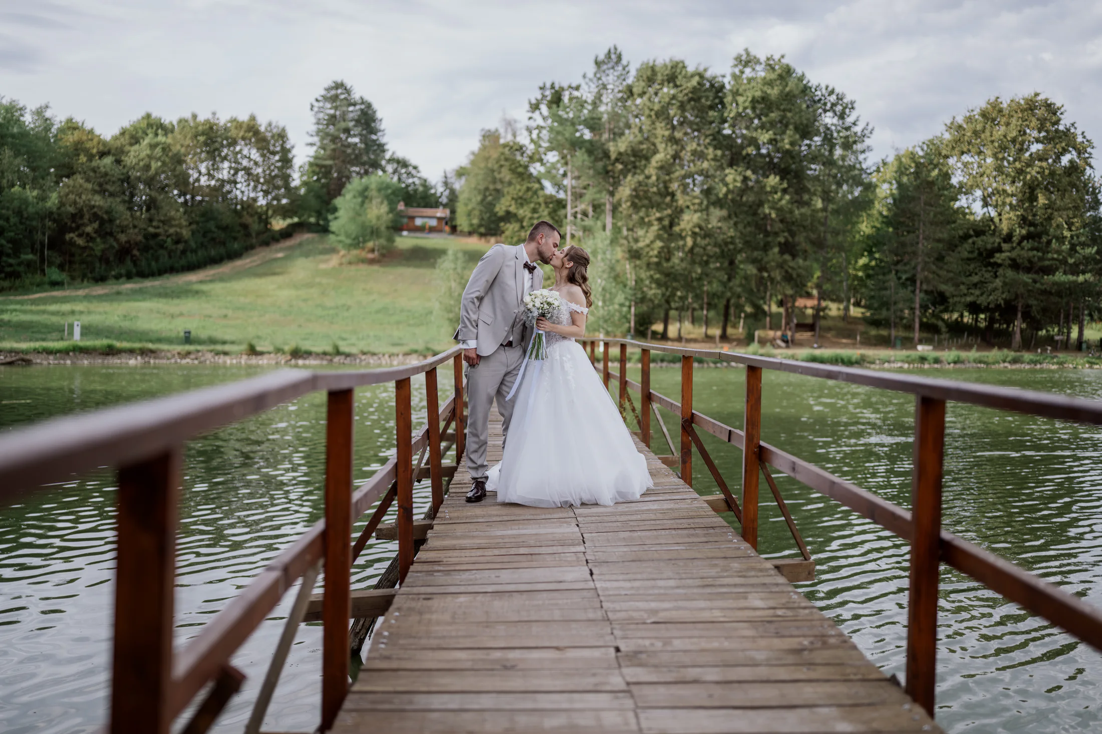 Bride and groom sharing a kiss on a wooden bridge